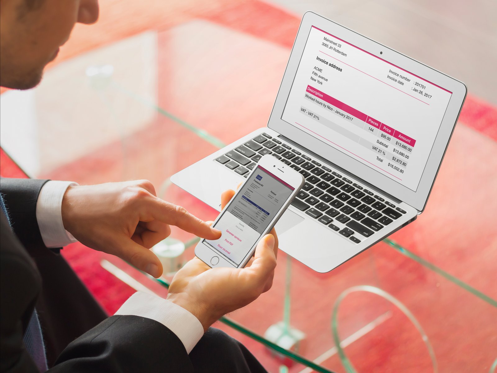 Freelancer app showing an invoice on a MacBook and the timesheet on an iPhone at a glass desk